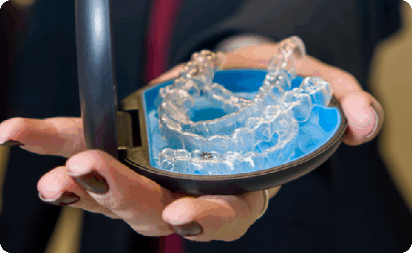 Alinhador transparente Invisalign sendo segurado por uma profissional